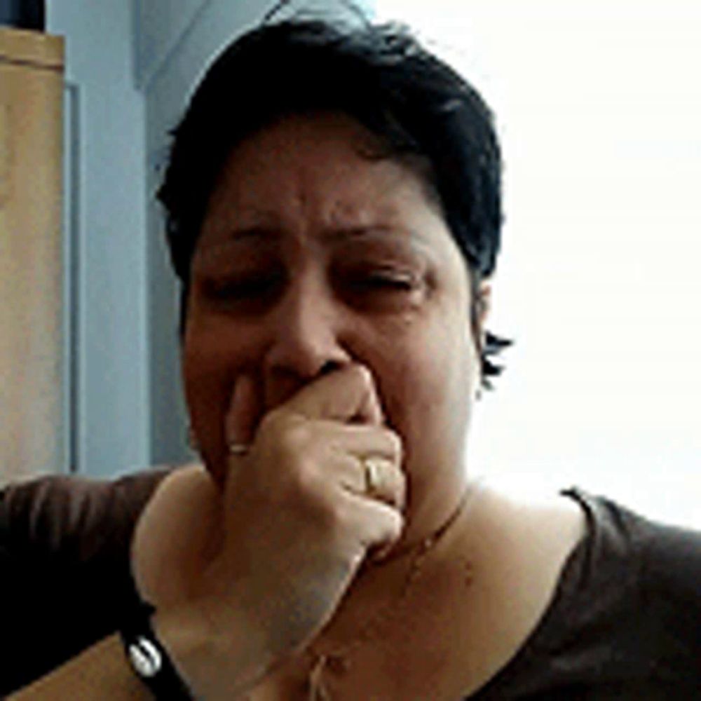 a woman covering her mouth with her hand while wearing a watch