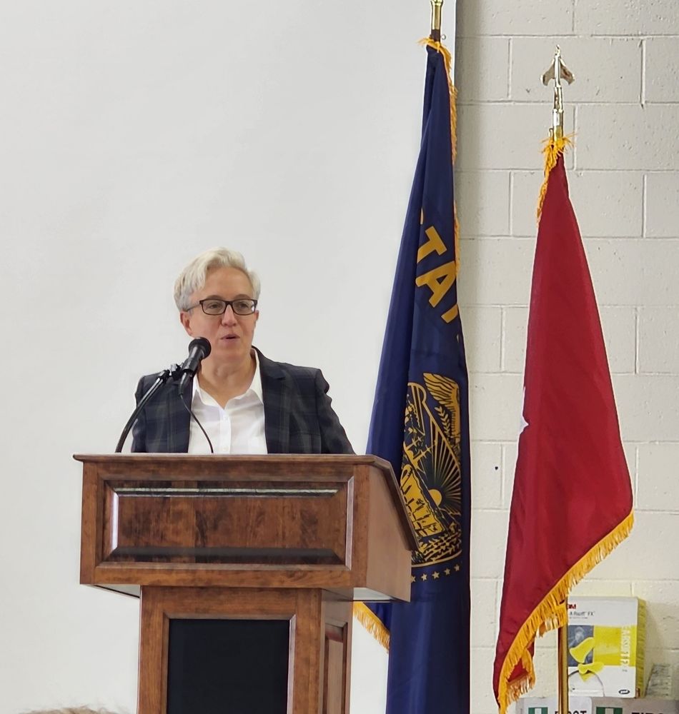 Governor Kotek at a podium with flags