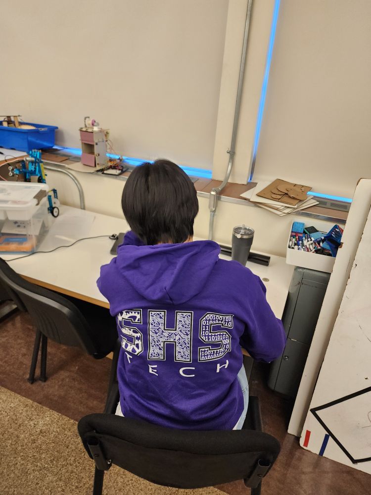 Student wearing purple sweatshirt at a desk