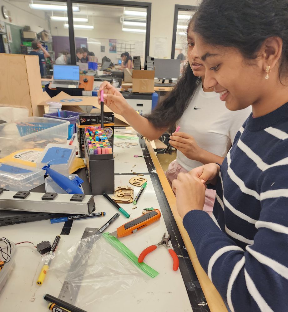 Students painting laser cut pieces at a work table