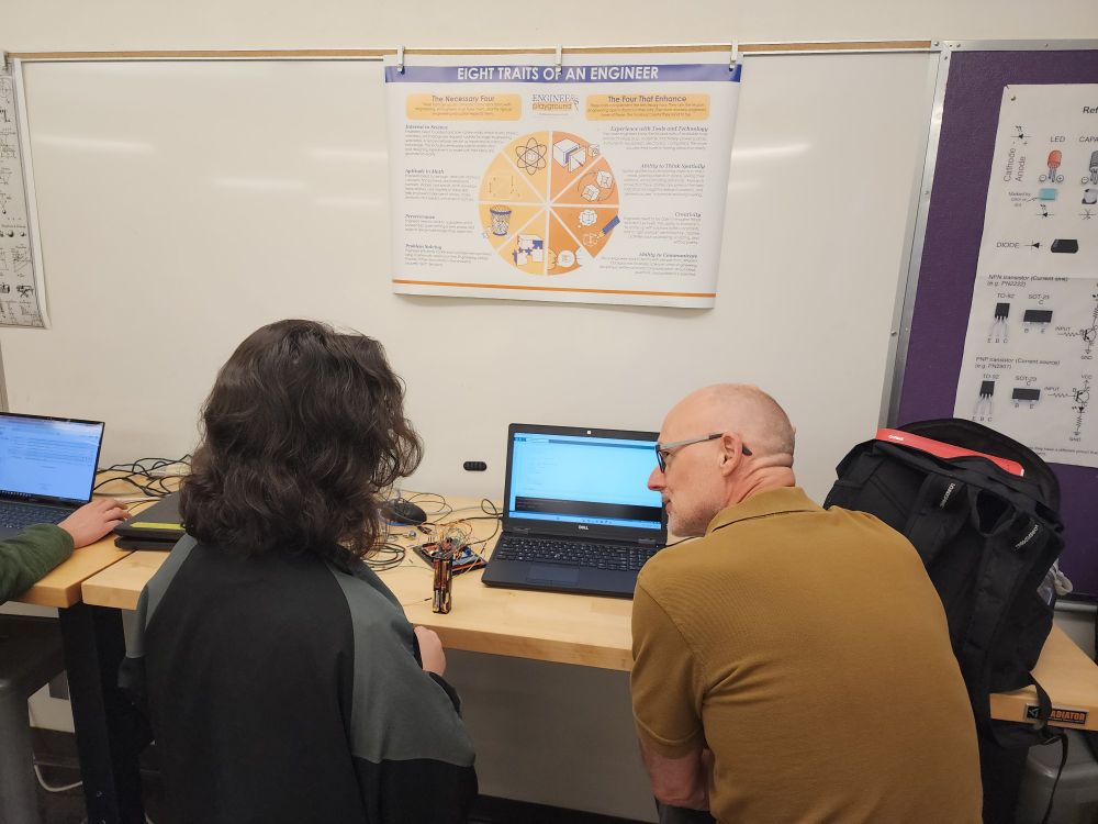 Student and engineer looking at a project and laptop