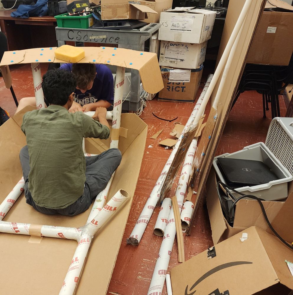 2 students building a cardboard boat