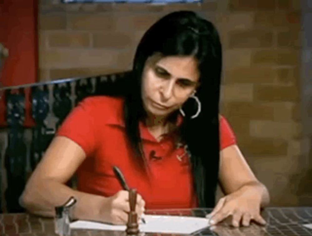 a woman is writing on a piece of paper with a pen .