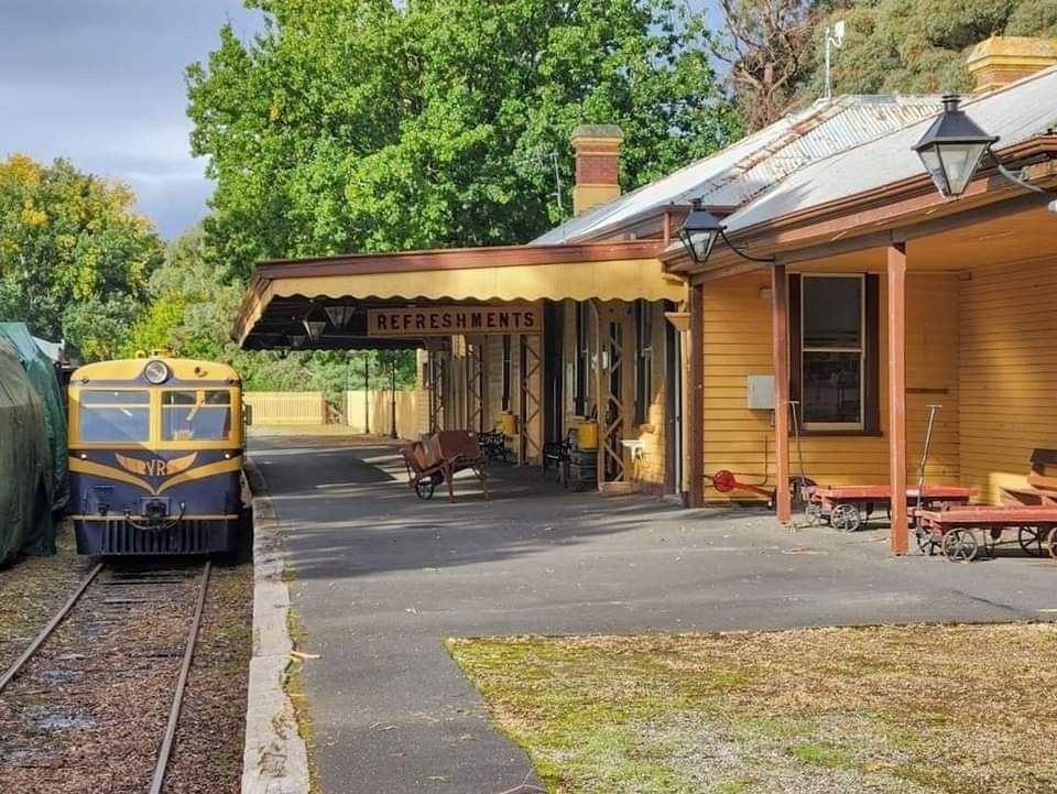 A view of the station platform, building, with a Walker Rail Motor docked waiting in the platform.