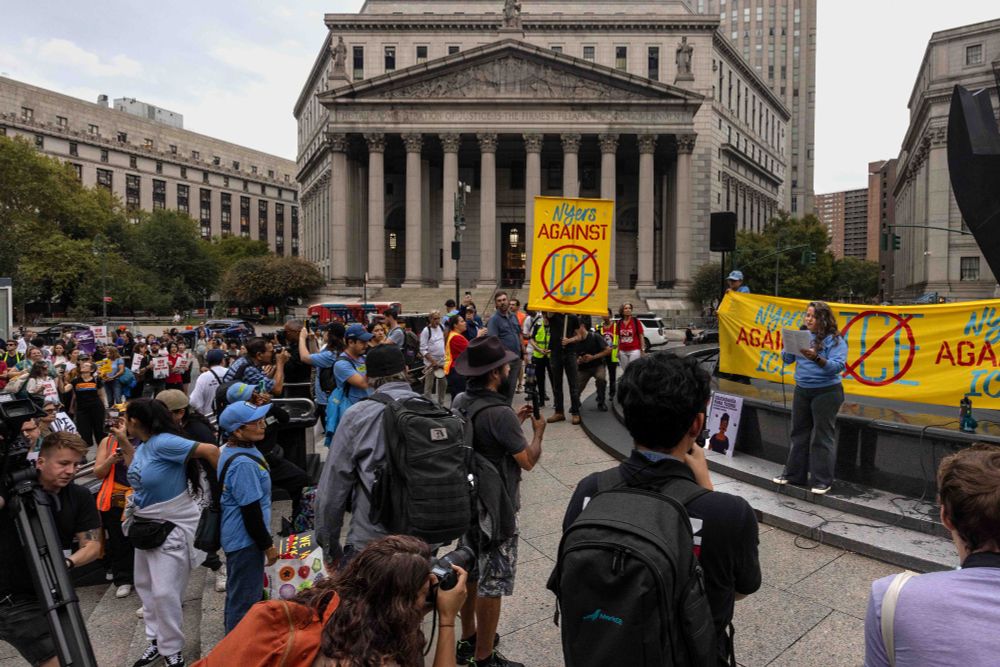 Center of Foley Square, across from the New York County Supreme Court. A speaker is in front of a banner protesting ICE