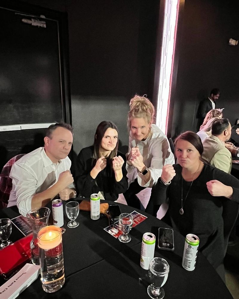 Eric, Anna, Emily, and Taylor holding up “boxing fists” at their table at the Sioux Falls Boxing Classic.