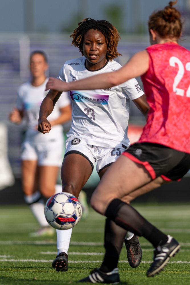 Junie Ejere pushing past a defender with a soccer ball.