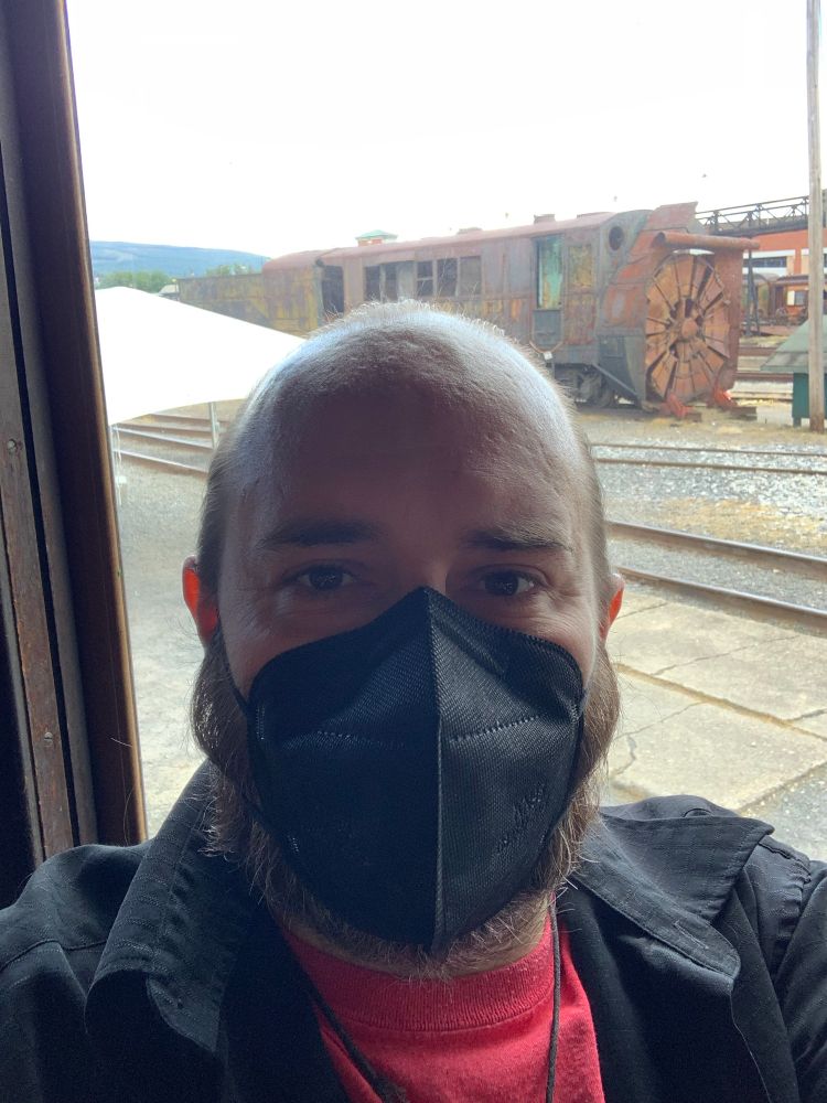 Poorly-lit selfie of me, masked, inside an old train car