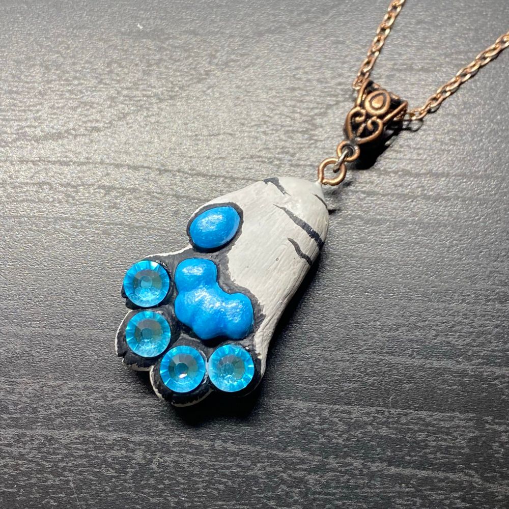 A pendant in the shape of a tiger's paw, with blue gems