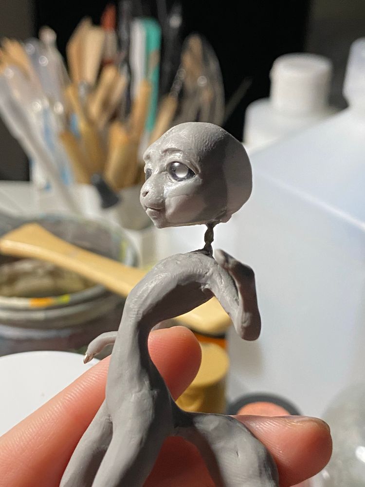 A later picture of the sculpture, with a neutral expression and black eyes with white pupils. He has a tiny muzzle, but looks very human in the face.