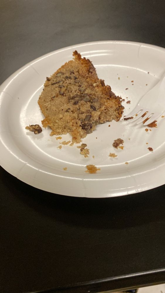 A partially eaten piece of banana bread on a paper plate.