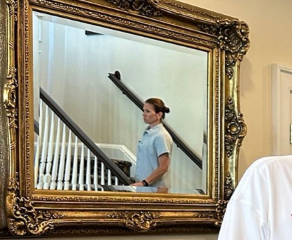 Zoom in on the woman in the mirror of the trump photo