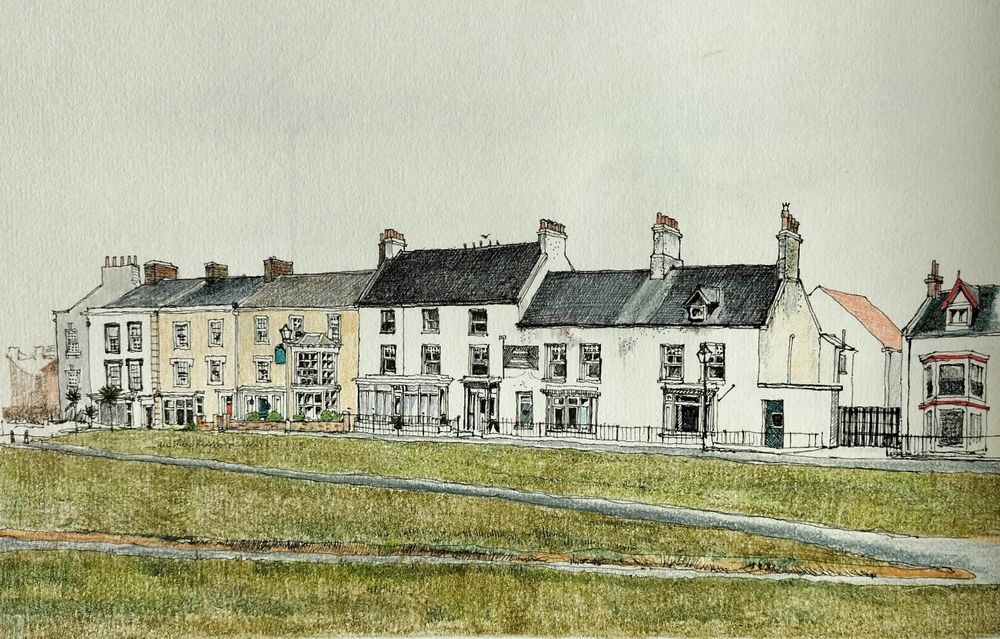 A row of houses facing a large open space filled with a grassed area crossed by footpaths. 