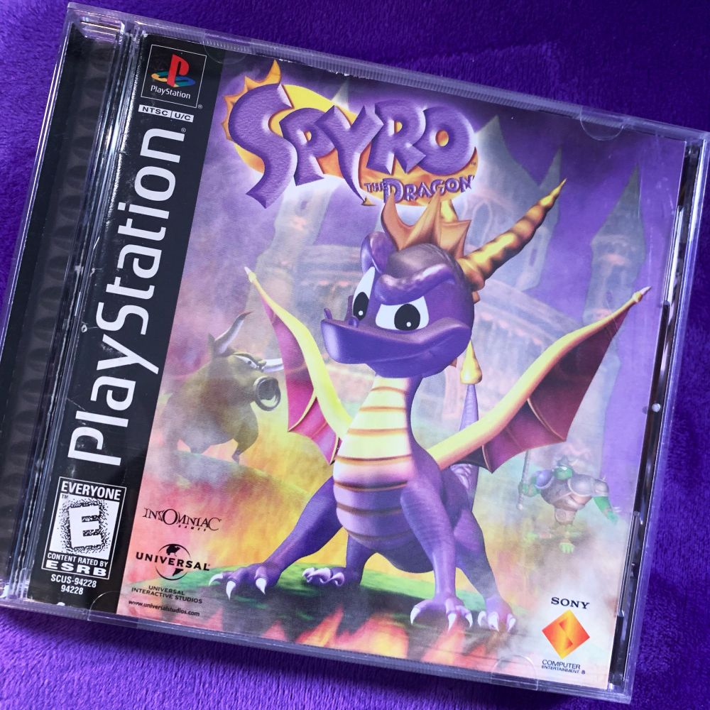 The PlayStation video game Spyro the Dragon lays on top a purple background.