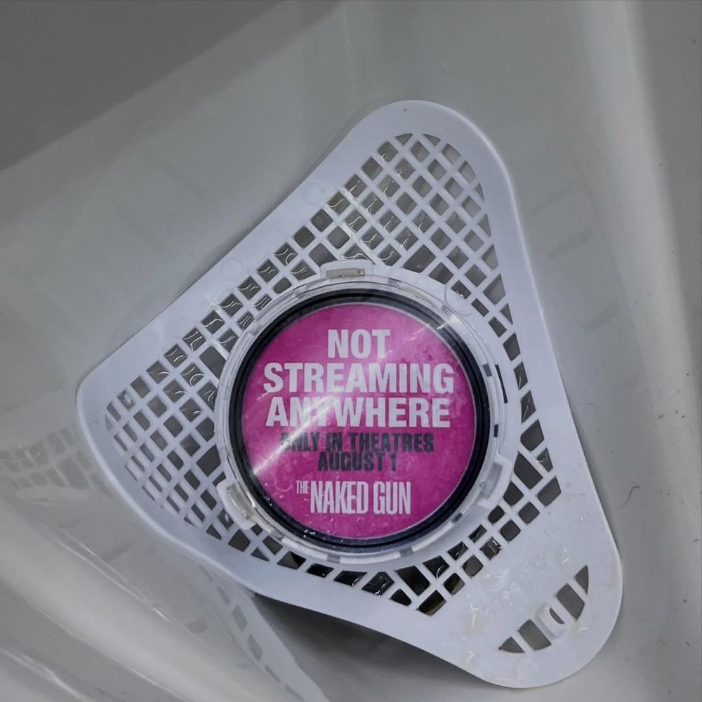 Urinal cake/insert that says "Not streaming anywhere; only in theaters August 1; The Naked Gun"