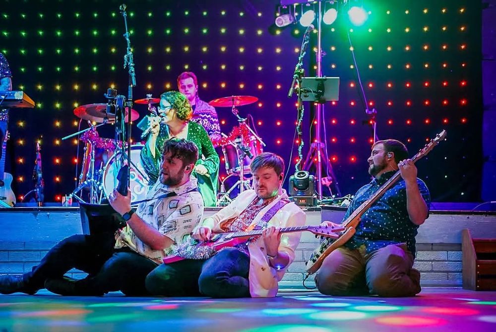 Cover band musicians kneeling on the stage floor in unison