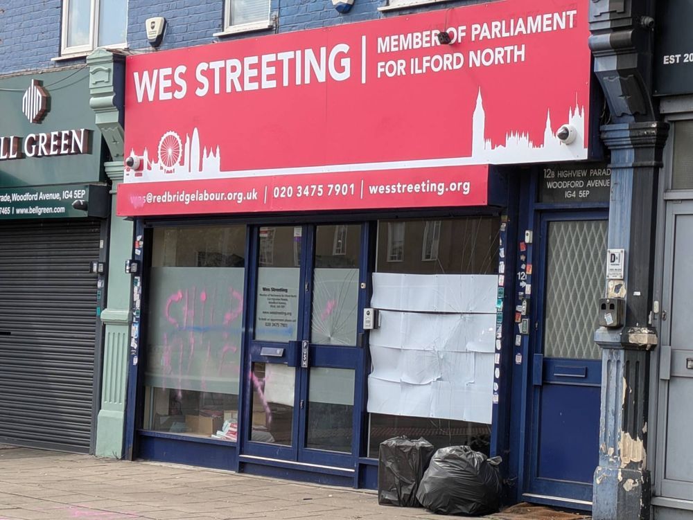 A different angle of Streeting's office, showing the CHILD KILLER text more visibly. Three punctures with spider-fractures are visible across the front of the office windows.