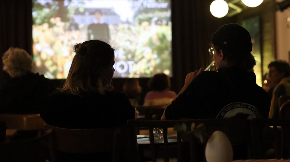 Das Foto zeigt Besucher von hinten während einer Vorführung im Filmklubb Offenbach. Auf der Leinwand ist unscharf ein Bild projiziert.