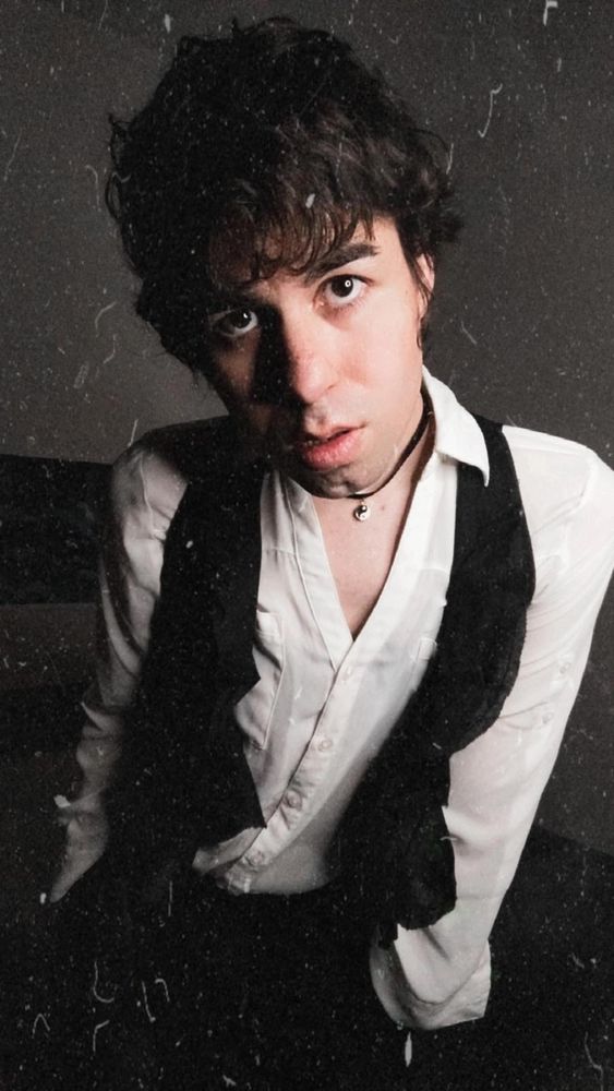 Neo @yoxneo posing with a white long sleeve button up shirt and a black vest, kinda seductively, with those lips and eyes 👀 oh my who can resist?! Lmao😏