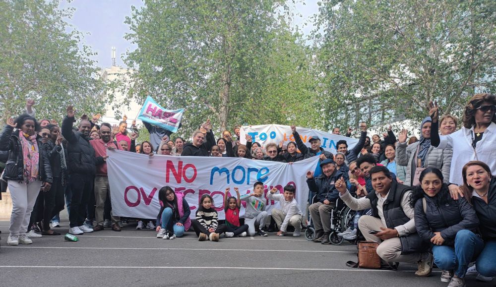A large group of HASL members holding banners - reading No More Overcrowding and Too Long In Temporary - pose for a photo.