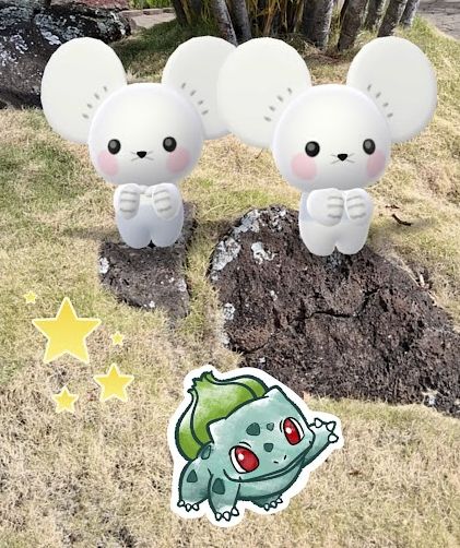 Tandemaus in Pokemon Go AR camera mode standing on two rocks with grass surrounding the area. A stars and Bulbasaur sticker is placed in front.