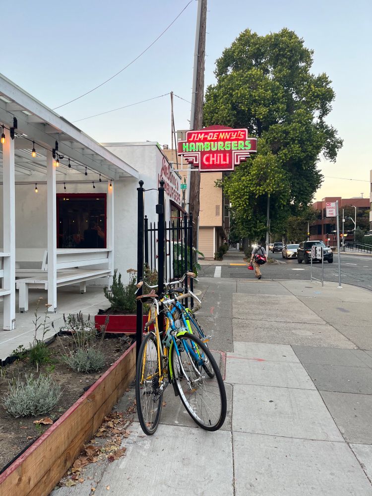 Jim Denny’s restaurant in Sacramento with neon sign and bikes parked out front at dusk.