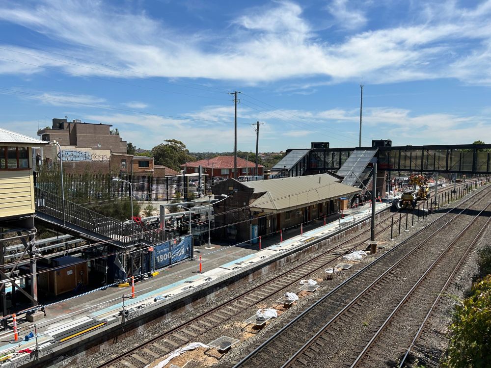 A view of Dulwich Hill Station from the Wardell Road bridge in late October 2024. Platform-screen doors have been installed on parts of the far side of the island platform, but not on the near side.