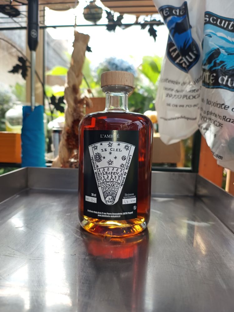 Photo d'une bouteille de whisky de la Distillerie Moby Dick à la Pointe du raz dans le Finistère en Bretagne. La bouteille est posée sur une plaque chauffante et le liquide est très brun.