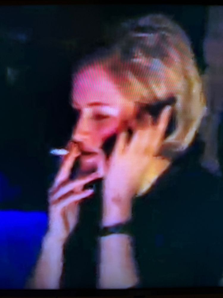 A blonde woman, smoking a cigarette and talking on a smartphone. IN 1999.