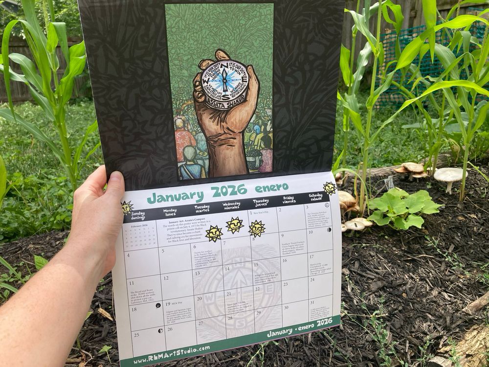 Green leafy background. In foreground, a hand holds a calendar page open to the month of January 2026 Enero.
Top of this calendar page features a brown hand holding a blue compass.