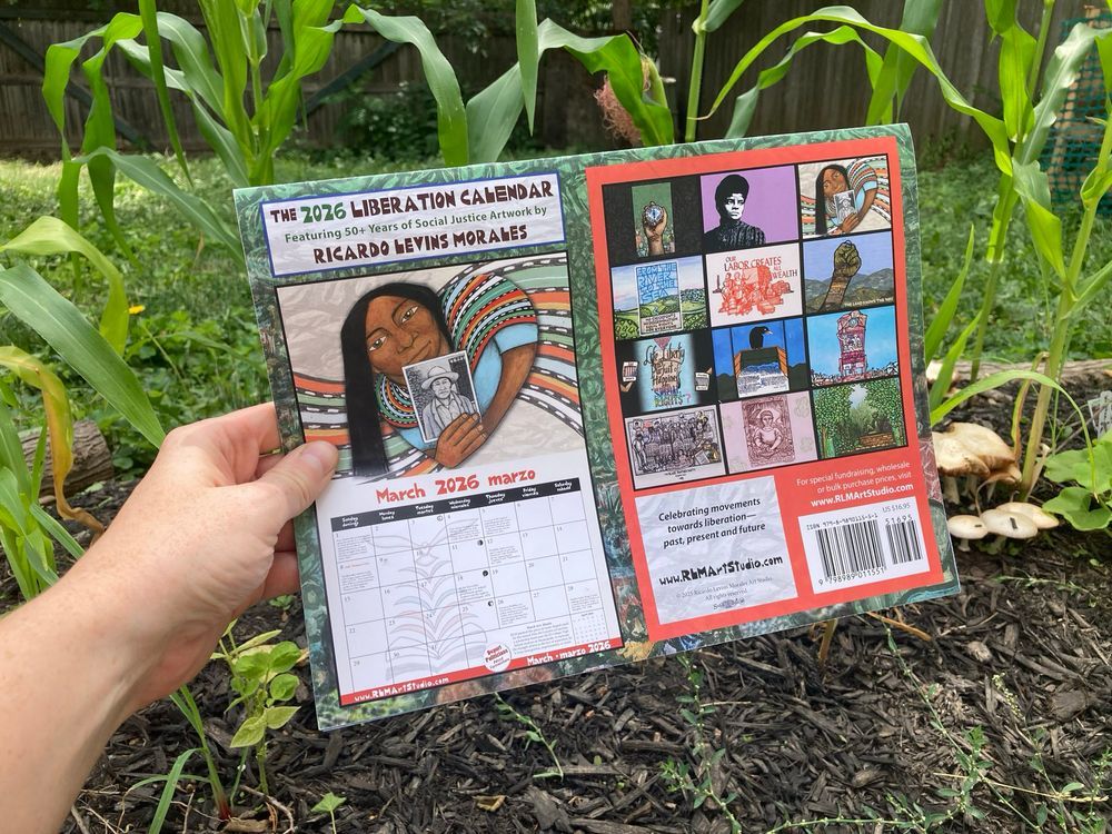 Green and grassy background. In foreground, a hand holds up a calendar. Calendar features preview images from each month. On left side of the back of this calendar features the month of March. March's graphic features a woman with a colorful shawl, holding a black and white portrait.