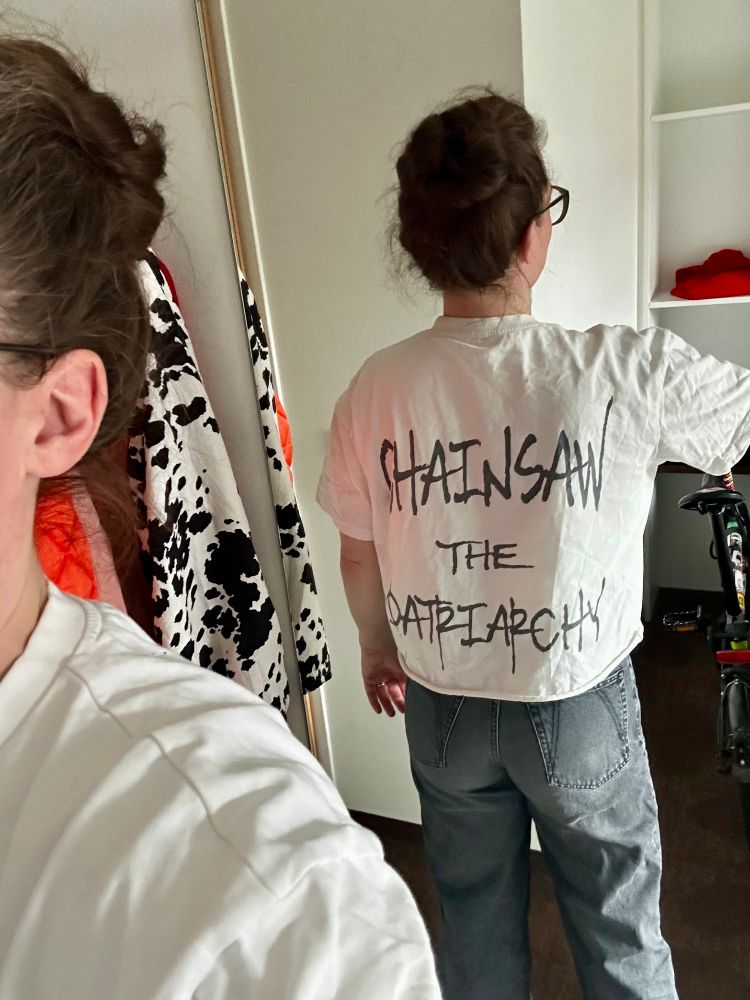 Katja is wearing a white t shirt with black letters "chainsaw the patriarchy".
