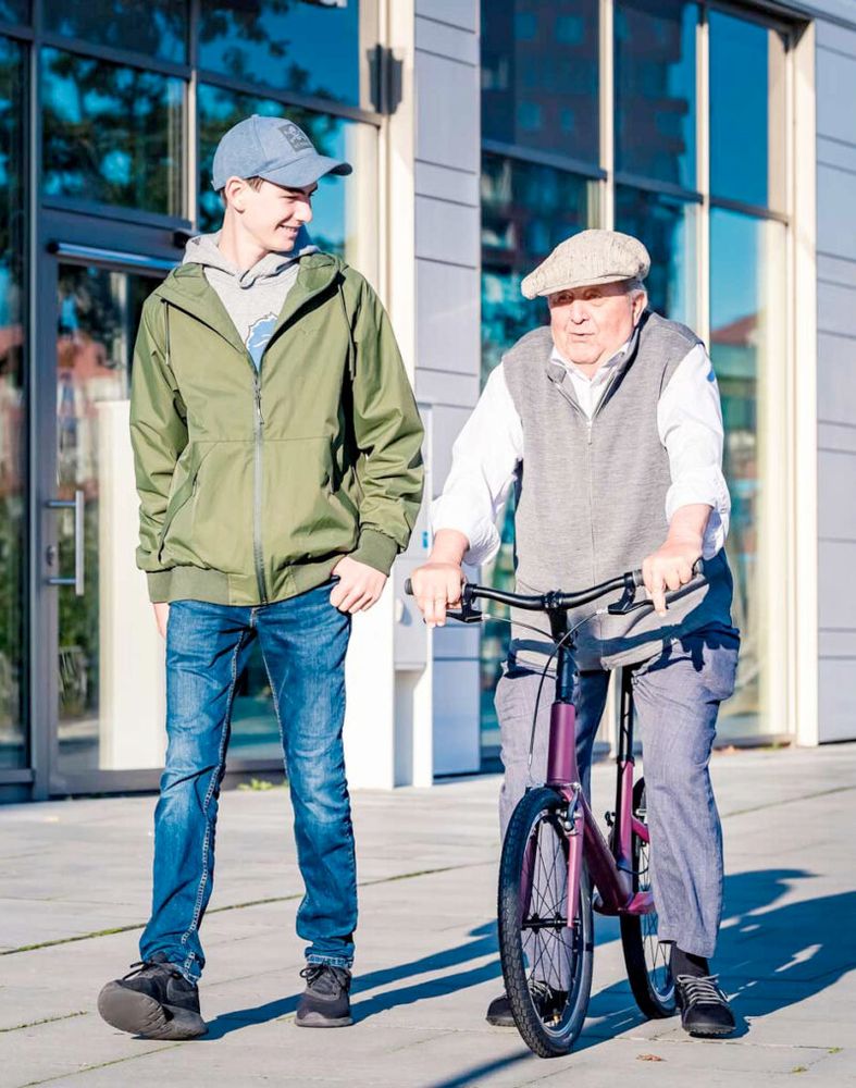 Two men - one is walking, another is using a walking bike for elderly