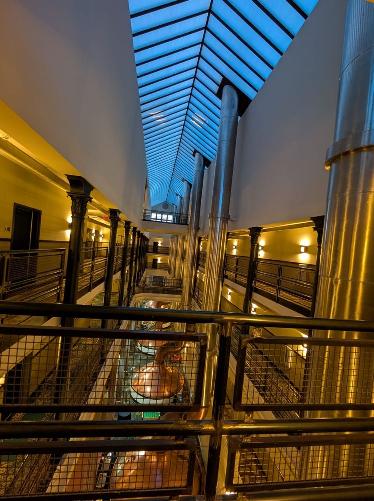 Image of hotel atrium, with exposed industrial brewery equipment incorporated into the building design. 