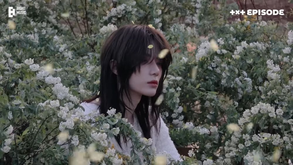 TOMORROW X TOGETHER 'Deja Vu' MV撮影ビハインド　神秘的で美しい長髪ボムギュさんが、花吹雪が舞う中で節目がちな表情演技をする様子