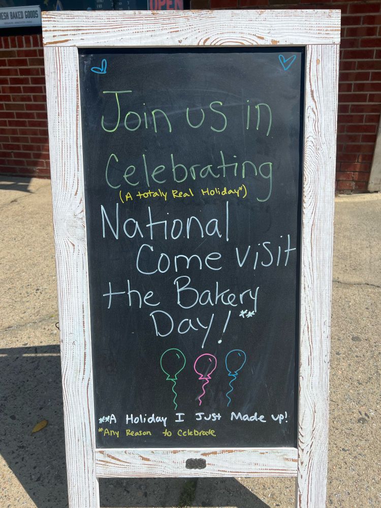 A sign outside the local bakery 

Join us in celebrating National Come Visit The Bakery Day. 
In smaller text it says (A totally real holiday)
And at the bottom (Holiday I just made up)
