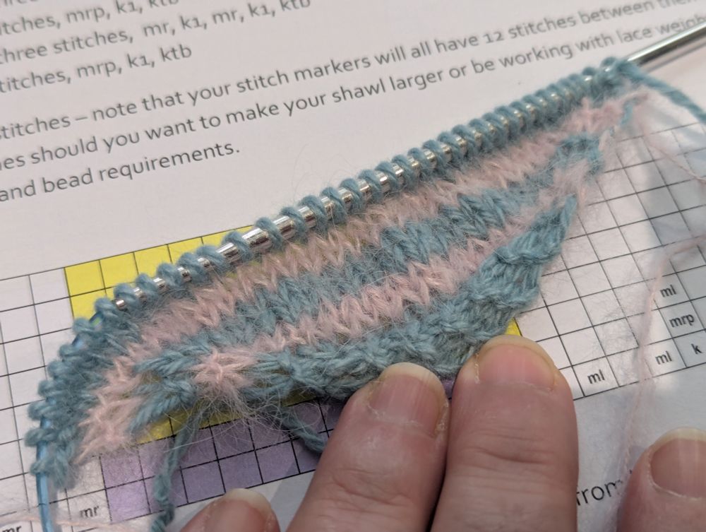 A very small start to a big knitting project featuring stripes of robin's egg blue cashmere and pink alpaca/silk fluff. A hand holds the hem down.