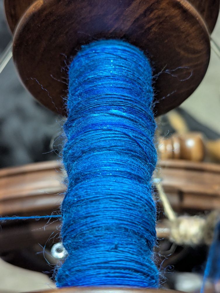 Blue laceweight, single-ply yarn has been spun on a walnut spinning wheel.