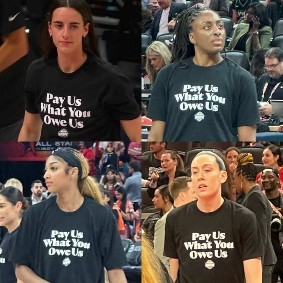 Four WNBA players pictured during warmups wearing black shirts with bold white text that reads ‘Pay Us What You Owe Us.’ The image captures different players at various moments on the court, surrounded by teammates and spectators. The shirts are part of a visible protest for fair compensation.