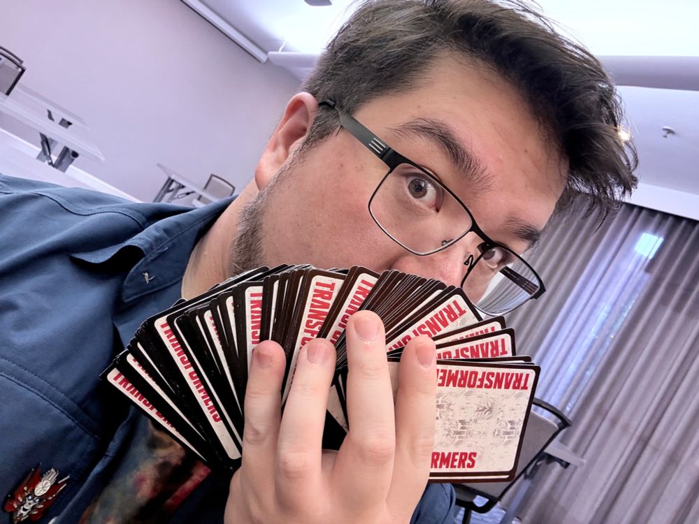 a man expertly fanning a large stack of rare cards from Transformers Trading Card Game with the cardistry expertise of a young Criss Angel, The Mindfreak