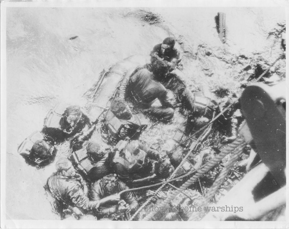 Oil-soaked Glowworm survivors wearing life preservers, in a half-submerged raft, cling to ropes hanging down from the Hippers deck. An incredible shot looking directly down from the heavy cruiser's deck to the desperate men below.