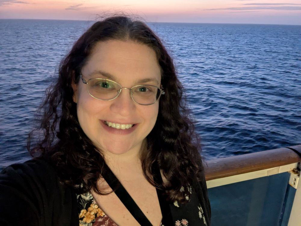 Woman in front of the ocean and sunset.