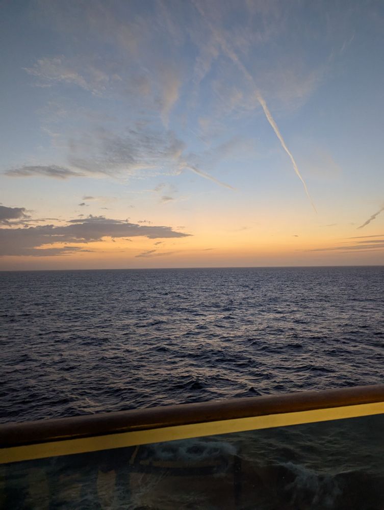 View of the ocean and sunset from a cruise ship balcony.