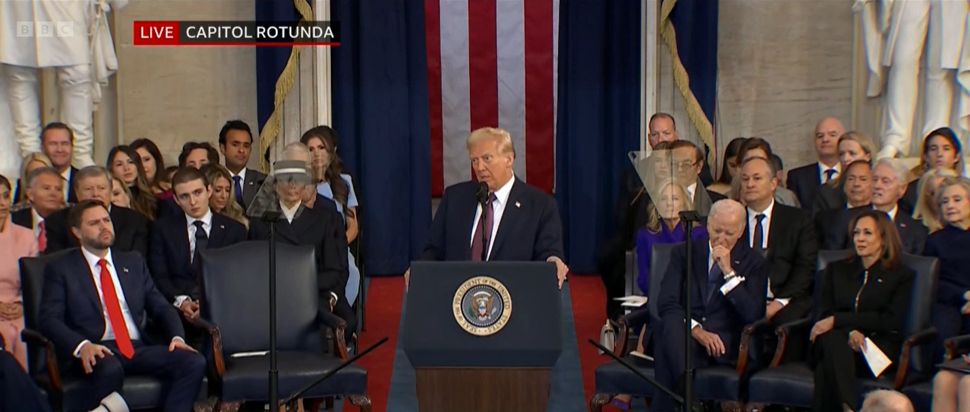 Trump speaks following his inauguration, with Biden and Harris seated behind.