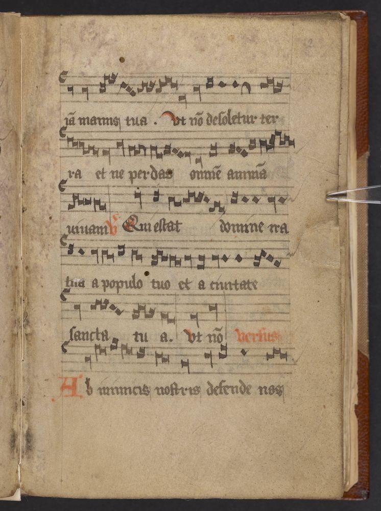 A yellowed page with music written across it in black notes. Black Latin text is under the lines of music