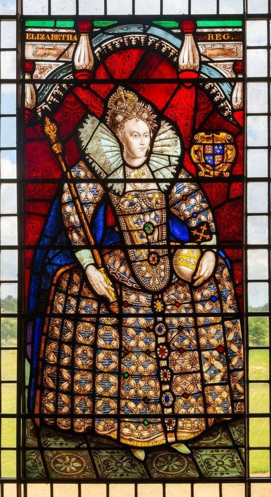 Stained glass window depicting Queen Elizabeth I, Melford Hall, Suffolk. Elizabeth is featured in red and gold with an elaborate crown and crown jewels.