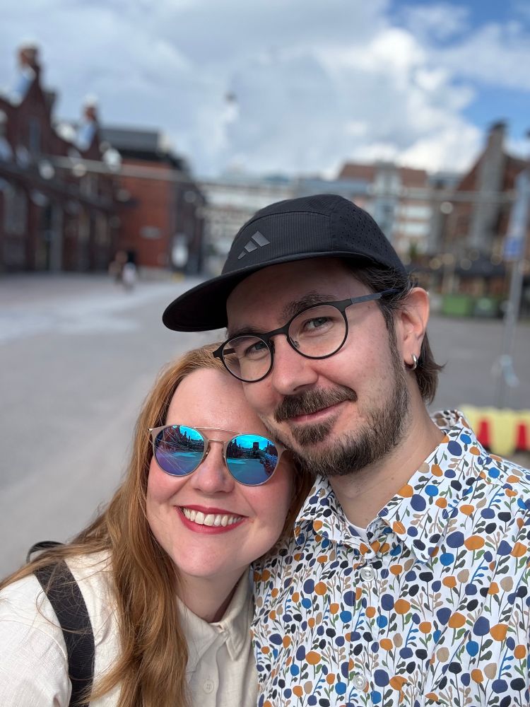 A portrait of two people smiling in an industrial setting. 
