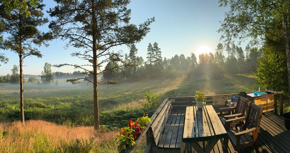 Sun rises over foggy fields, as viewed from a cabin terrace. 