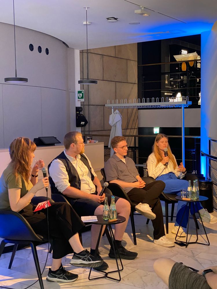 Foto vom Podium. Neben der Moderatorin ganz links sitzen Lukas Boch, Felix Zimmermann und Alina Menten. 