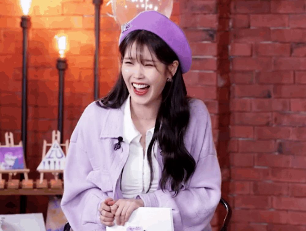 a woman wearing a purple jacket and a purple beret is smiling